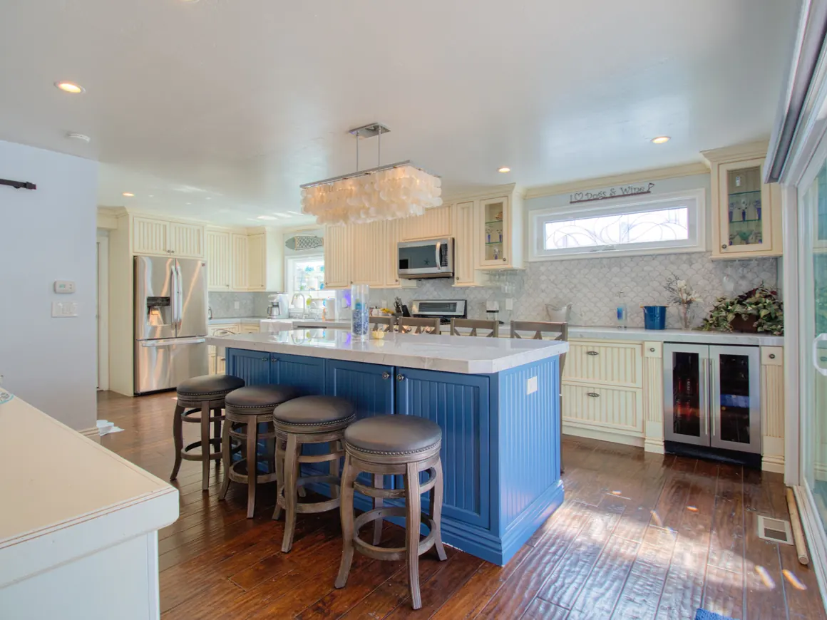 Coastal kitchen with a blue island and custom cabinetry