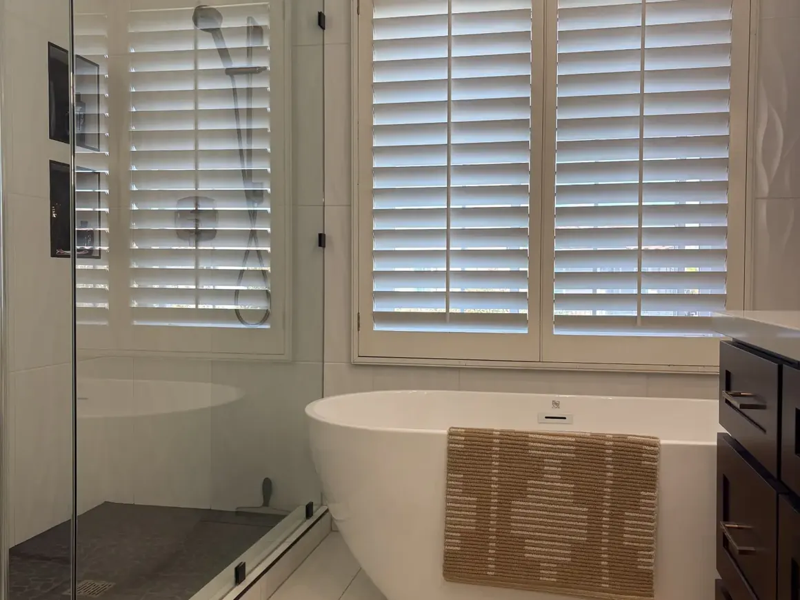 Primary bathroom with a freestanding tub and plantation shutters